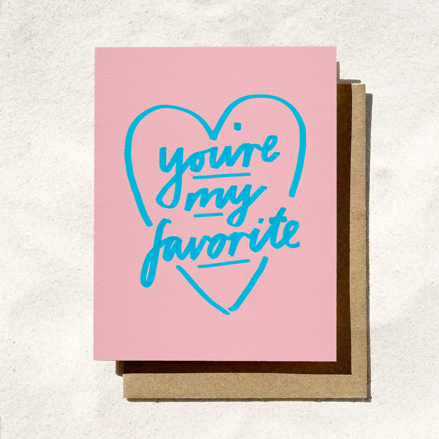 Pink card with blue text 'you're my favorite' on a textured surface