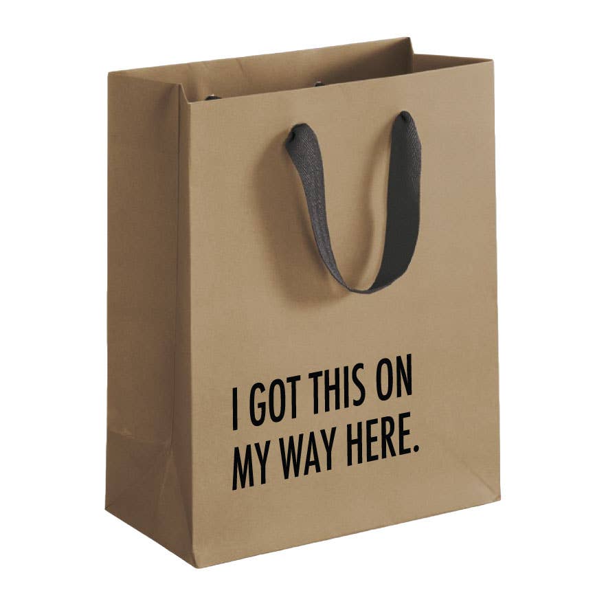 Brown paper bag with black text 'I GOT THIS ON MY WAY HERE.' on a white background