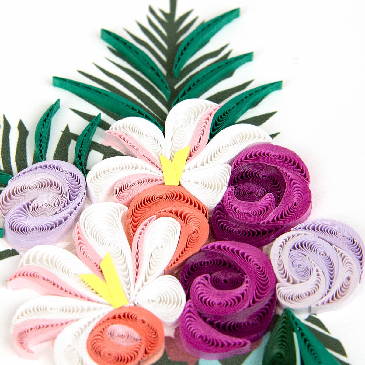 Colorful paper flower arrangement with green leaves on a white background