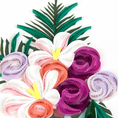 Colorful paper flower arrangement with green leaves on a white background